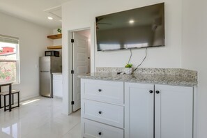 A modern kitchen with a flat-screen TV, white cabinets, and a granite countertop. - Walkable & Modern! South Padre Studio By Beach (South Padre Island)