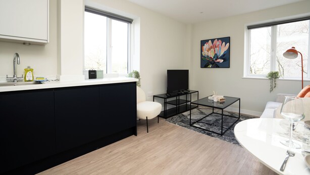 A modern kitchen with a black island, a dining area with a white table, and a large window with a view. - Church House by Guestz (Filton)