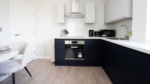 A compact kitchen with a dishwasher, microwave, and a sink. - Church House by Guestz (Filton)
