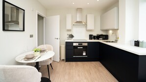 A modern kitchen with black cabinets, a white countertop, and a built-in oven. - Church House by Guestz (Filton)