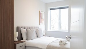 A bedroom with a bed, bedside tables, a window, and a door. - Church House by Guestz (Filton)