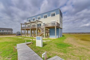 Un edificio de dos pisos con terraza de madera y zona exterior cubierta.