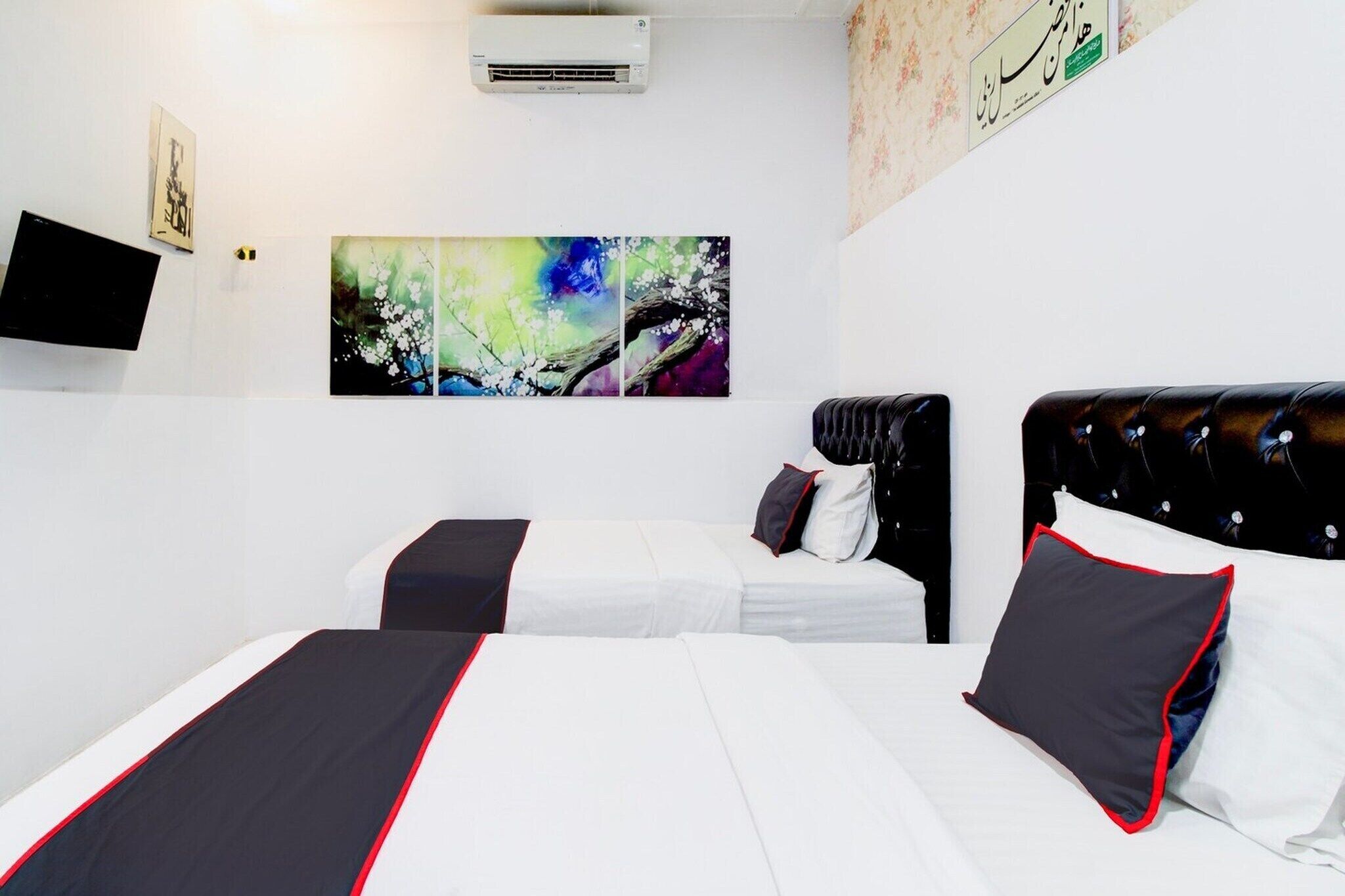 Ein Hotelzimmer mit zwei Betten, einem Flachbildfernseher und abstrakter Wandkunst.