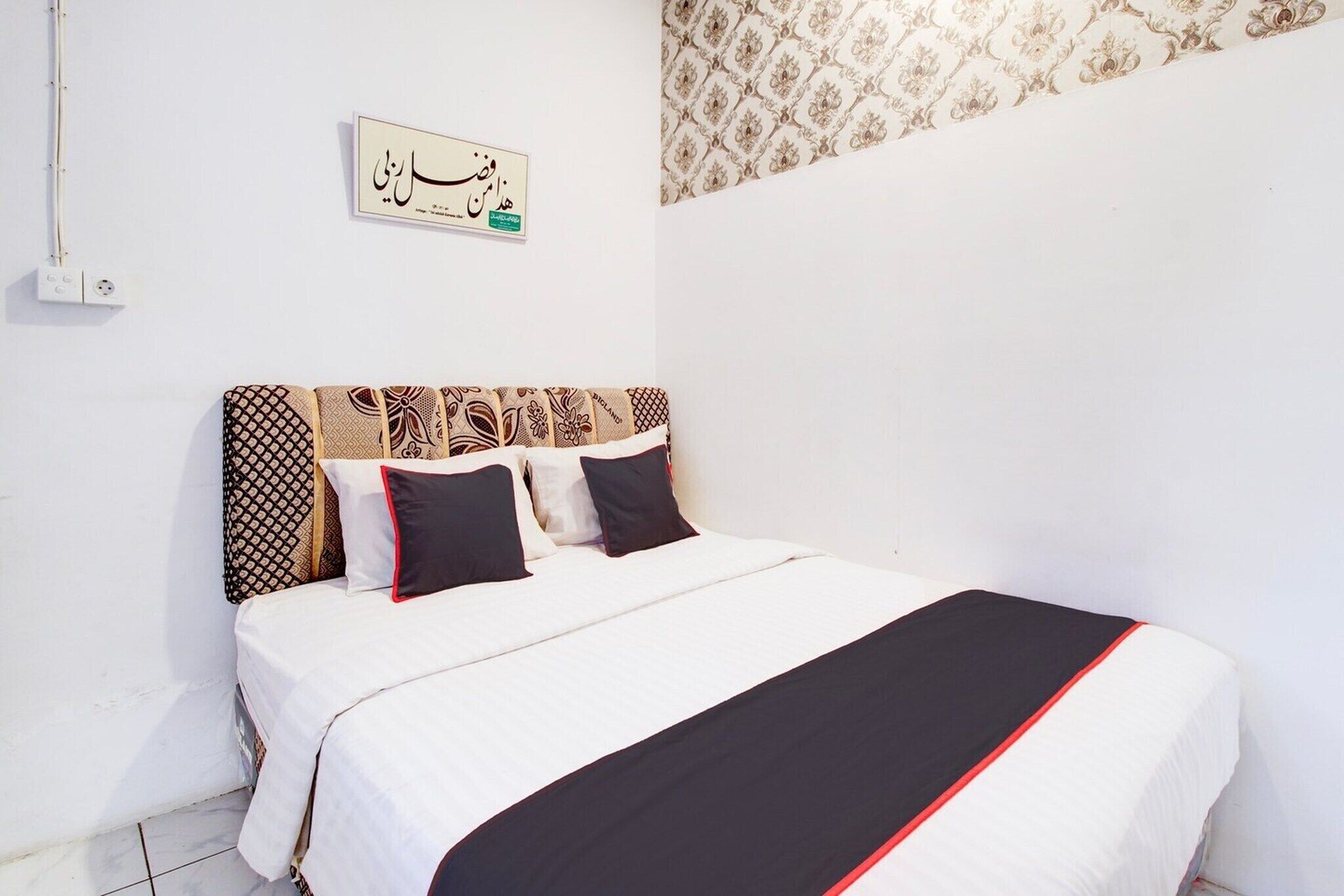 Un dormitorio con cama, cabecera estampada y un letrero en la pared.