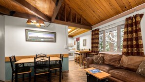 A cozy interior with a dining area, a sofa, and a kitchen in the background. - Rustic Charm Condo #16 at Ptarmigan Village (Whitefish)