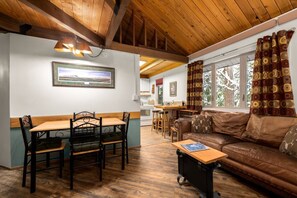 A cozy interior with a dining area, a sofa, and a kitchen in the background. - Rustic Charm Condo #16 at Ptarmigan Village (Whitefish)