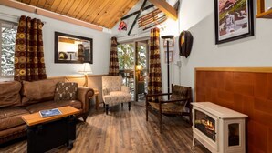 A cozy living room with a sofa, armchair, and a fireplace. - Rustic Charm Condo #16 at Ptarmigan Village (Whitefish)