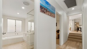 A modern bathroom with a glass shower enclosure, a bathtub, and a large mirror. - 3BR Comfortable Home (Edgewater)