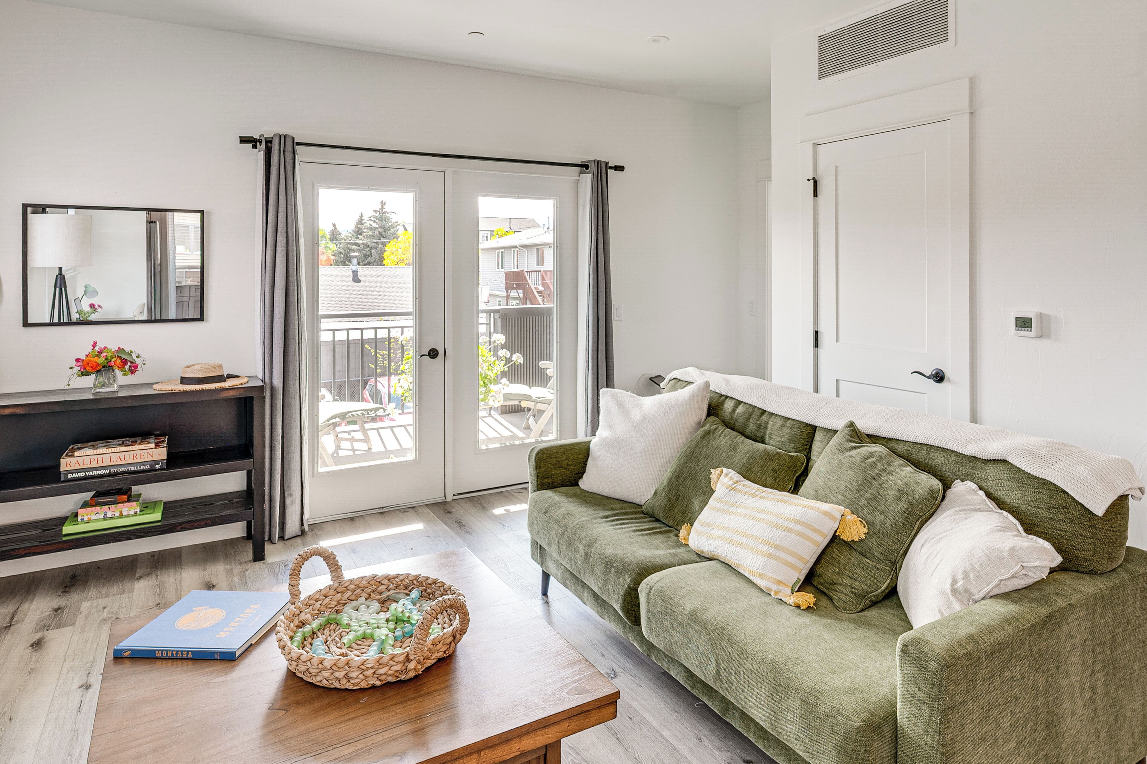 A living room with a green sofa, a wooden coffee table, a basket, and a bookshelf with books.