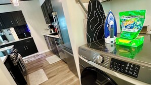 Una cucina moderna con lavatrice, ferro da stiro e detersivo per bucato.