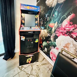Ein Pac-Man-Automaten in einem Raum mit floraler Wandmalerei.