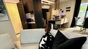 Un soggiorno moderno con un divano, un'area pranzo e una cucina sullo sfondo.