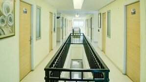 Ein langer, schmaler Korridor mit Türen, die mit 024 und 025 nummeriert sind, einer zentralen Treppe und einer Deckenleuchte.