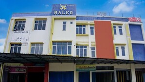 Ein mehrstöckiges Gebäude mit einem Schild für 'MALEO' und 'Coyo' im obersten Geschoss, einem Schild für 'Girl Studioo' im zweiten Stock und einem Schild für 'MALEO Laundry' im Erdgeschoss.