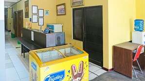 Zona de recepción con mostrador, banca, máquina expendedora y dispensador de agua.