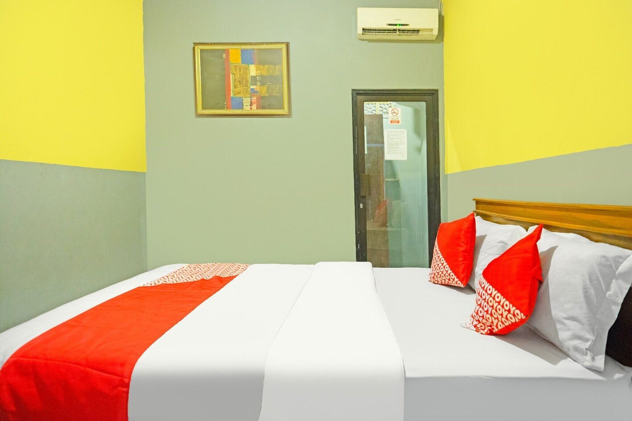 Een hotelkamer met een bed, een deur en een wandgemonteerde airconditioner.