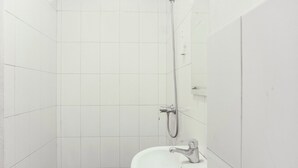 A small, white bathroom with a sink and a shower.