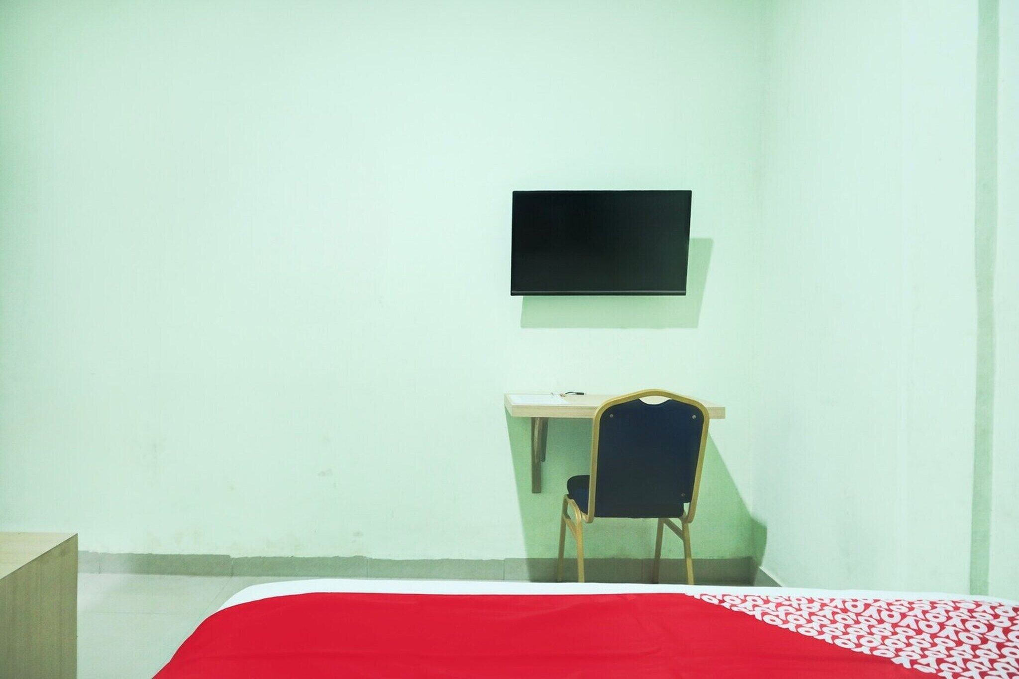 Une chambre comprenant un lit, un bureau, une chaise et un téléviseur fixé au mur.
