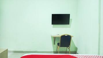 Une chambre comprenant un lit, un bureau, une chaise et un téléviseur fixé au mur.