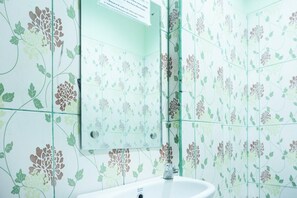 Un baño con azulejos de estampado floral, un espejo y un lavabo.