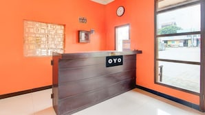 Un comptoir d’accueil avec une enseigne indiquant « OYO », une horloge et une fenêtre donnant sur la rue.