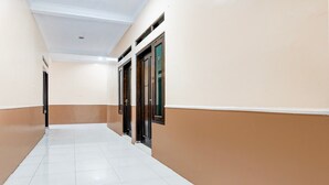 A hallway with white tiled flooring, beige walls, and dark wooden doors.