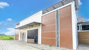A modern building with a flat roof, large windows, and a paved entrance area.