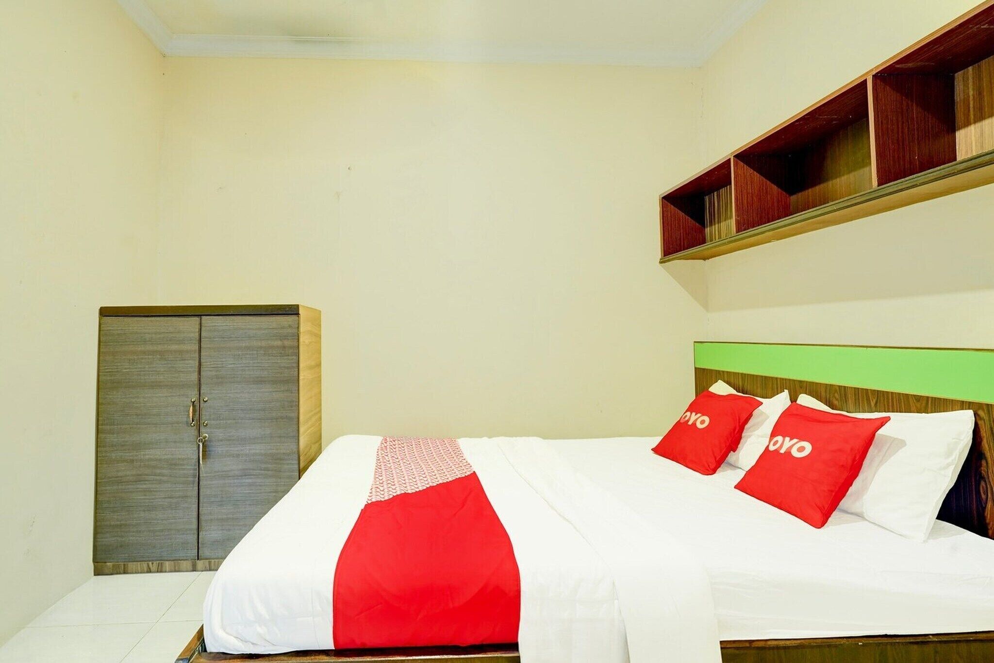 Une chambre d’hôtel avec un lit, une armoire et une étagère au-dessus du lit.