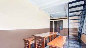 A room with a wooden table and benches, a staircase, and a door.