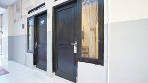 A hotel entrance with two dark-colored doors, a tiled floor, and a window with a curtain. - Luxury Deluxe DBL Retreat W/ Free WiFi and Parking (Yogyakarta)