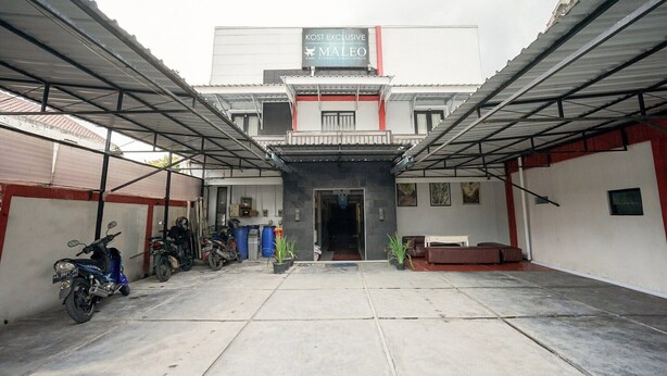 A building with a sign reading 'KOST EXCLUSIVE MALEO' and a covered parking area with motorcycles. - Luxury Deluxe DBL Retreat W/ Free WiFi and Parking (Yogyakarta)