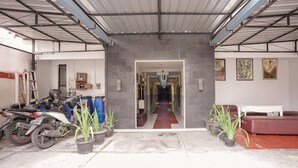 A garage with a motorcycle, potted plants, and a red carpet leading to a hallway. - Luxury Deluxe DBL Retreat W/ Free WiFi and Parking (Yogyakarta)