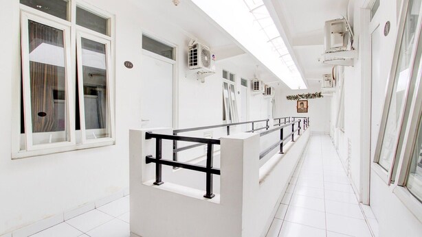 A hallway with white walls, multiple windows, and air conditioning units. - Cozy Double Escape W/ Free WiFi and Parking (Yogyakarta)