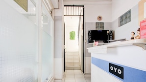 A hotel reception area with a tiled floor, a staircase leading to an outdoor area, and a counter with a sign reading 'OYO'. - Cozy Double Escape W/ Free WiFi and Parking (Yogyakarta)