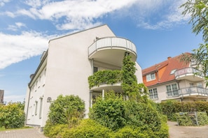 Ein modernes Gebäude mit einem geschwungenen Balkon, umgeben von Grünflächen.