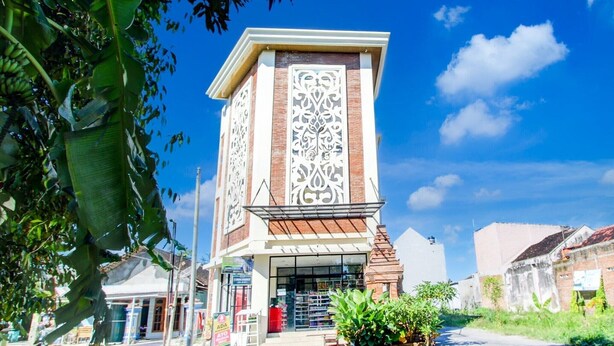 Un edificio con una torre central que presenta intrincados diseños blancos, rodeado de follaje y otros edificios.