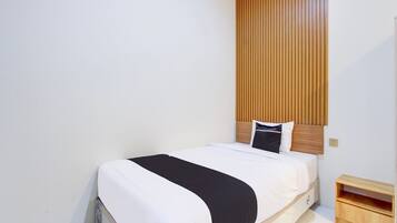 Ein Einzelbett mit Holz Kopfteil, einem Nachttisch und einem an der Wand befestigten Regal.