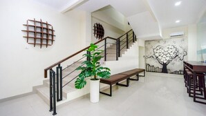Eine Treppe mit Holzgeländer, ein weißer Topfpflanze und eine Wand mit einem Baum-Wandbild.