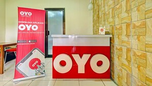 Ein Empfangsschalter mit einem großen 'OYO'-Schild, einem roten Banner zur Werbung für die OYO-App und einer Wand mit Steinmuster.