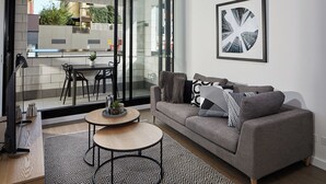 Una sala de estar moderna con un sofá gris, una alfombra estampada y una mesa de centro redonda.
