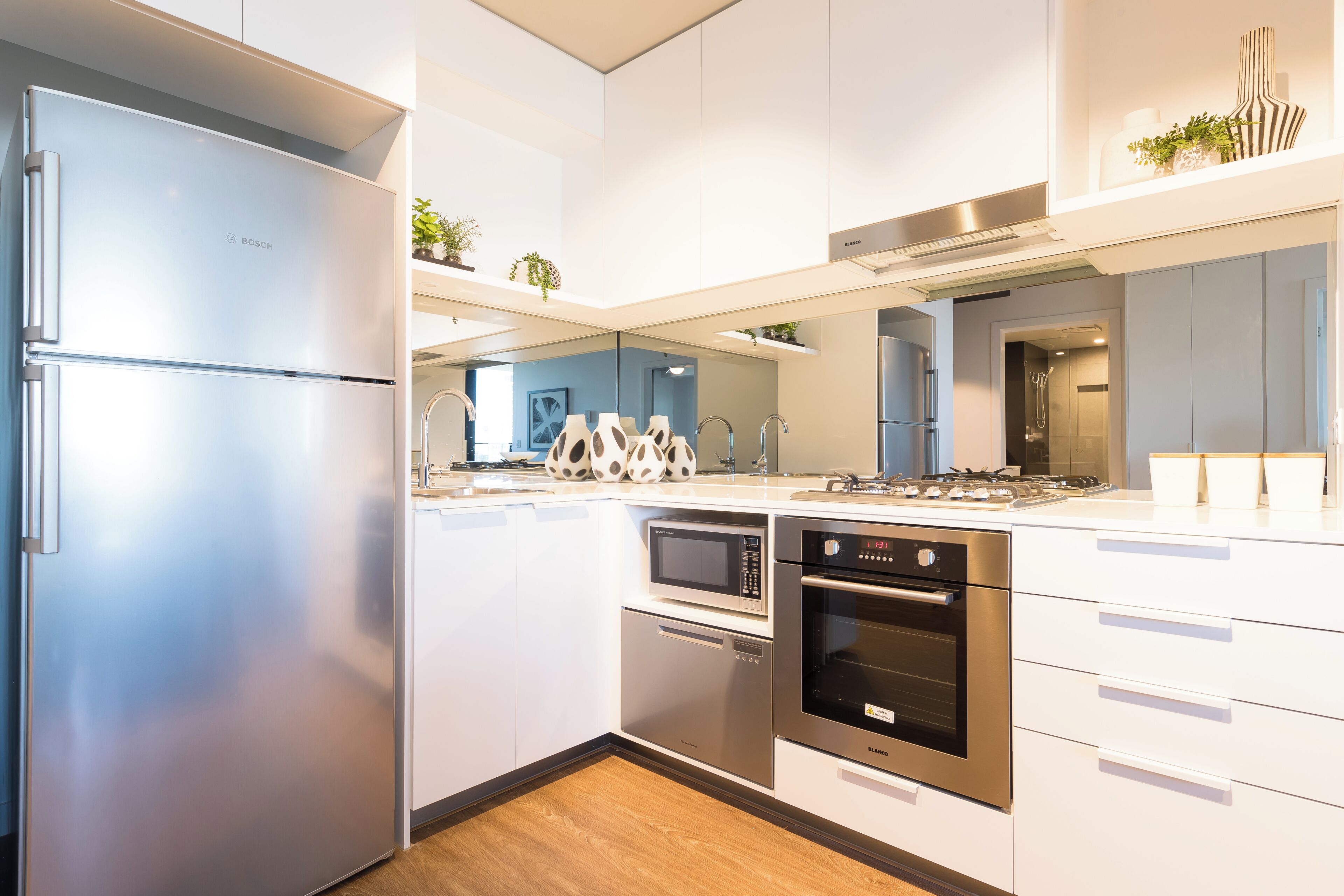 A modern kitchen with stainless steel appliances, white cabinetry, and a built-in microwave.