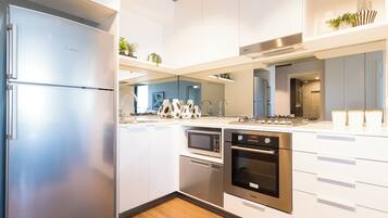A modern kitchen with stainless steel appliances, white cabinetry, and a built-in microwave.