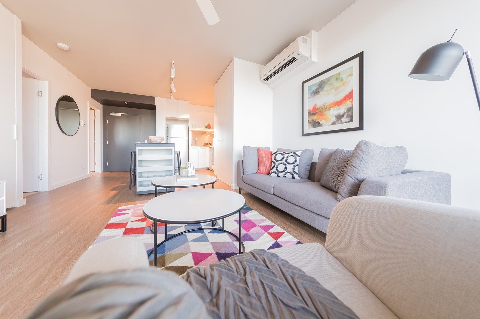 A modern living room with a grey sofa, a round coffee table, and a colorful rug.