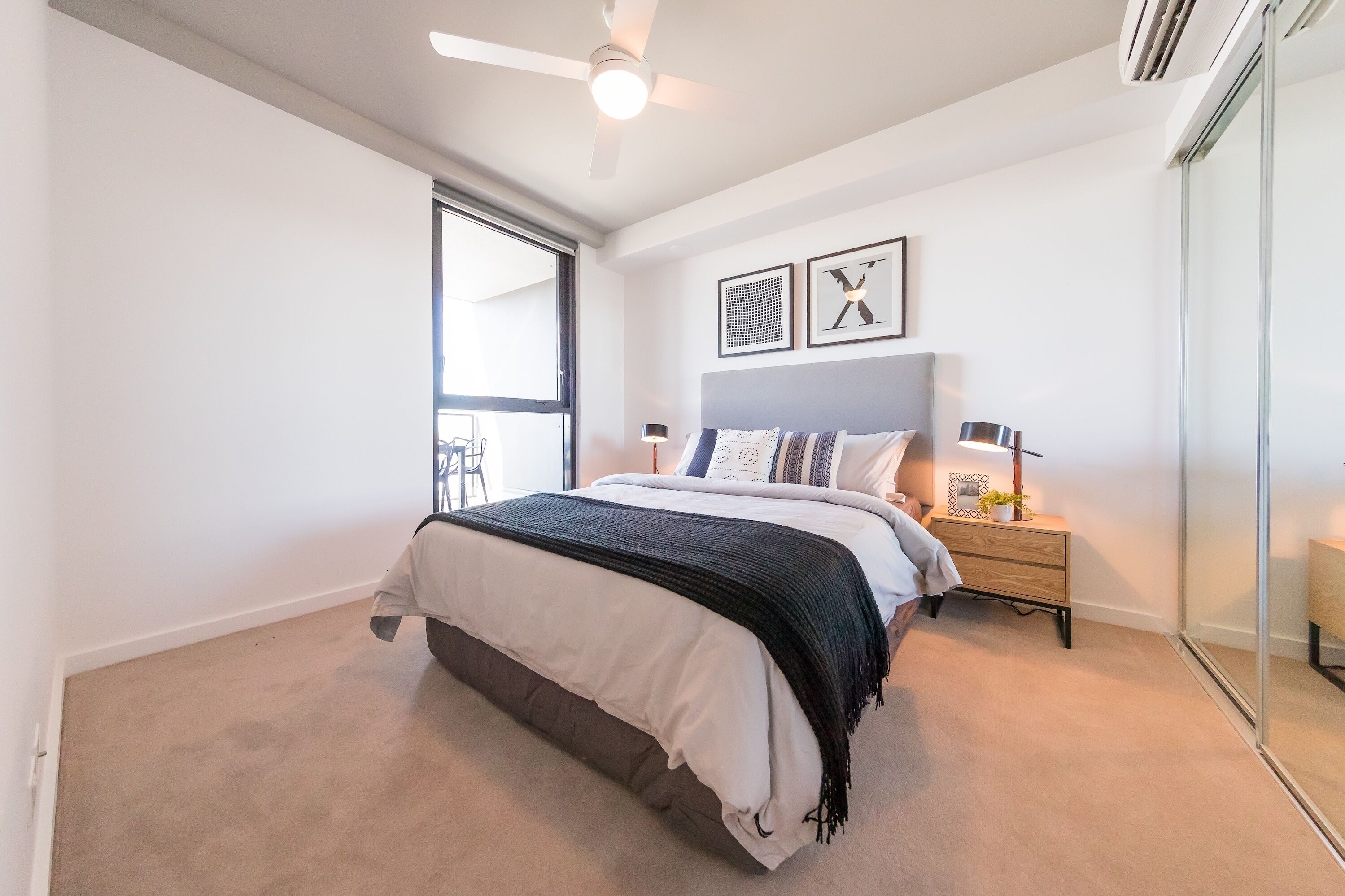 A bedroom with a bed, bedside tables, a ceiling fan, and a window.