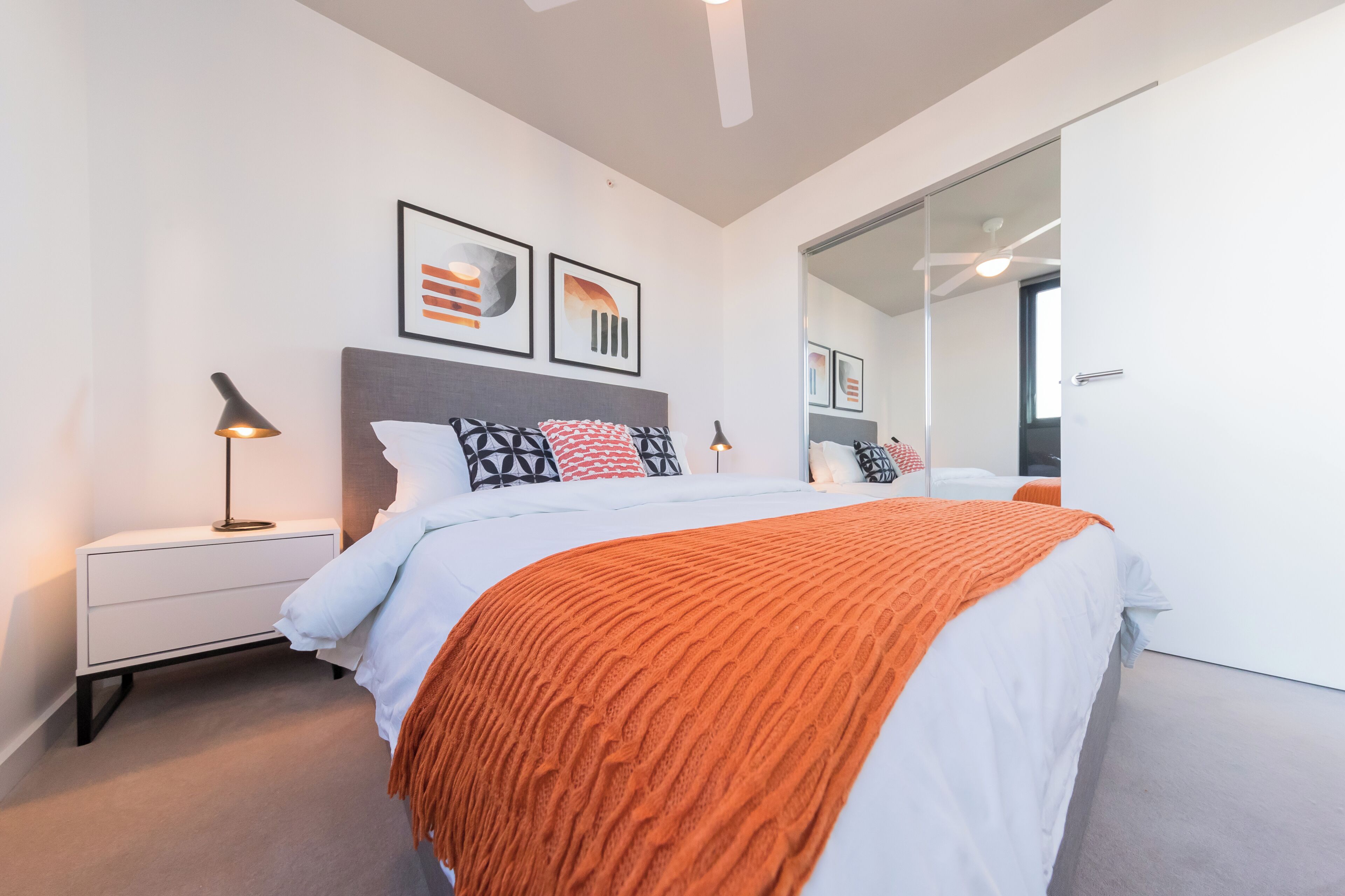 Un dormitorio moderno con cama, mesita de noche, lámpara y decoración en la pared.