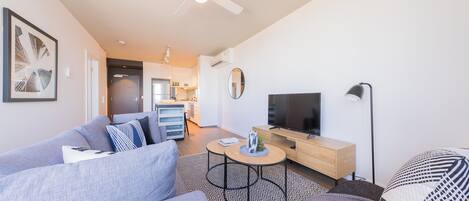 A modern living room with a sofa, coffee table, TV, and a ceiling fan.