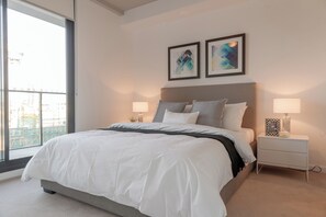 Un dormitorio moderno con una cama grande, lámparas de noche y arte abstracto en la pared.