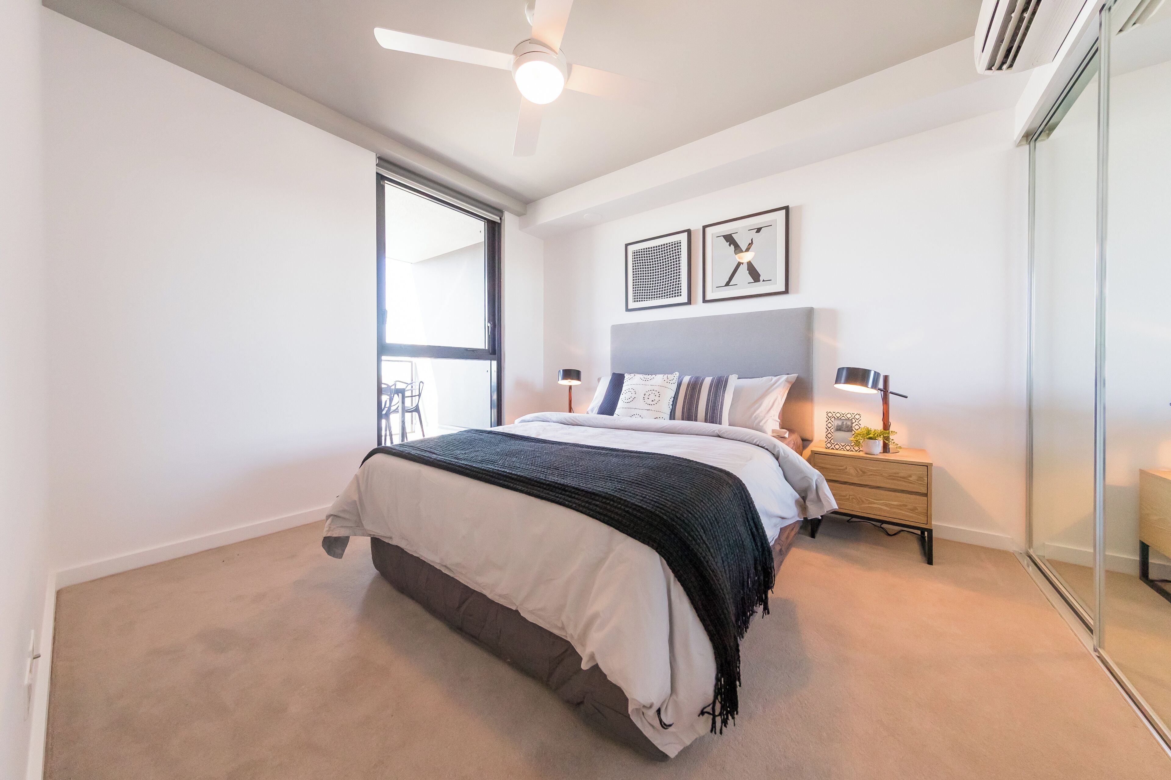 A bedroom with a bed, bedside tables, a ceiling fan, and a large window.