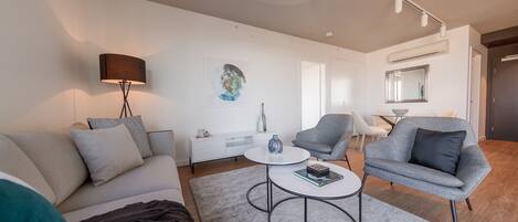A modern living room with a sofa, armchairs, a coffee table, and a painting on the wall.