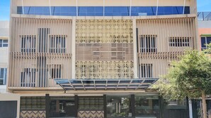 Un bâtiment moderne doté d’un panneau décoratif central, de grandes fenêtres et d’une entrée abritée.